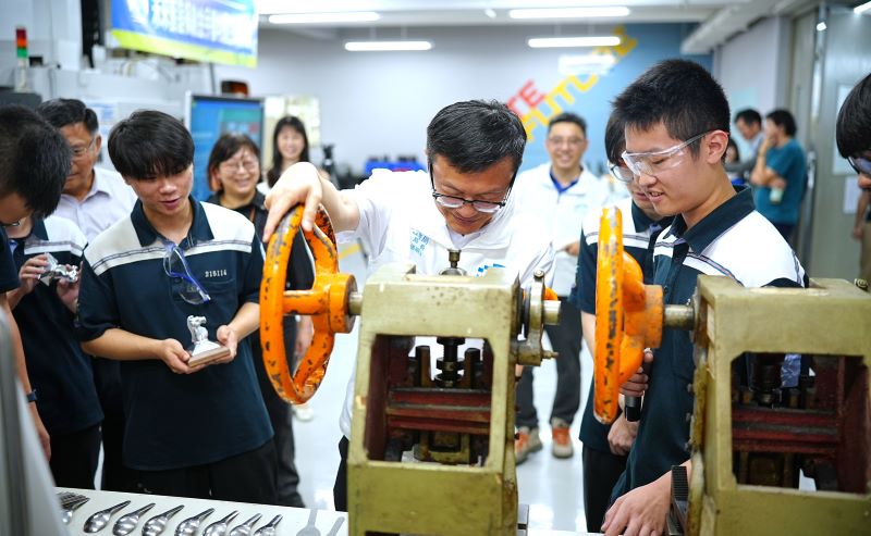 《圖說》模具科柯宥名同學(右1)教張明文局長操作不鏽鋼湯匙模具手動沖壓。〈教育局提供〉