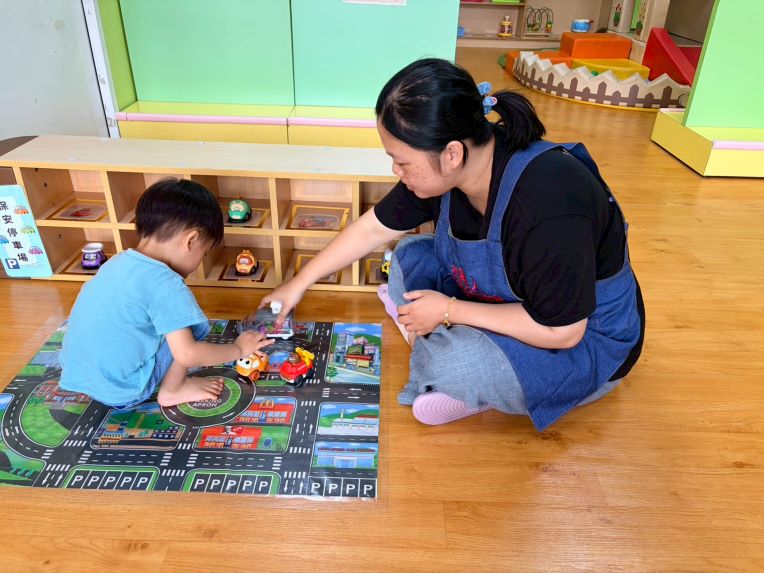 《圖說》樹林保安公托中心親子館定點臨托的托育人員陪幼兒一起玩汽車。〈社會局提供〉